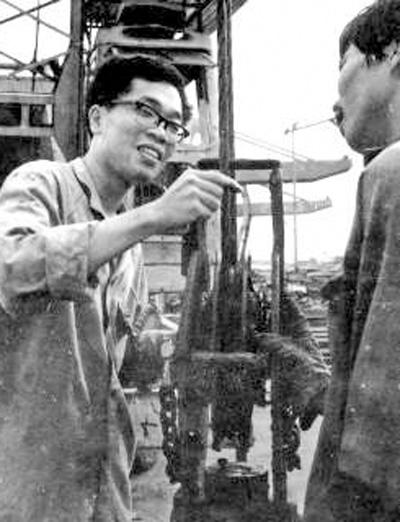 包起帆(左)在上海港码头和工友一道研究装卸货物工作中存在的问题(资料照片)。新华社发